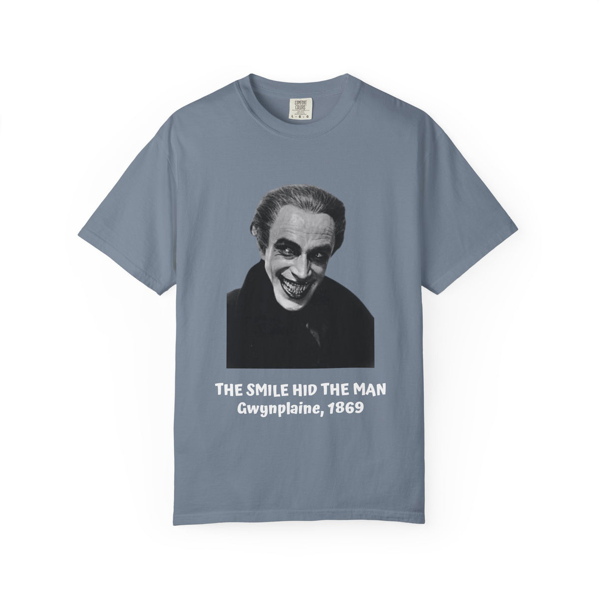 The Man Who Laughs Gwynplaine T-shirt in Chambray blue, worn outside a bookshop — 'The Smile Hid the Man, Gwynplaine 1869'