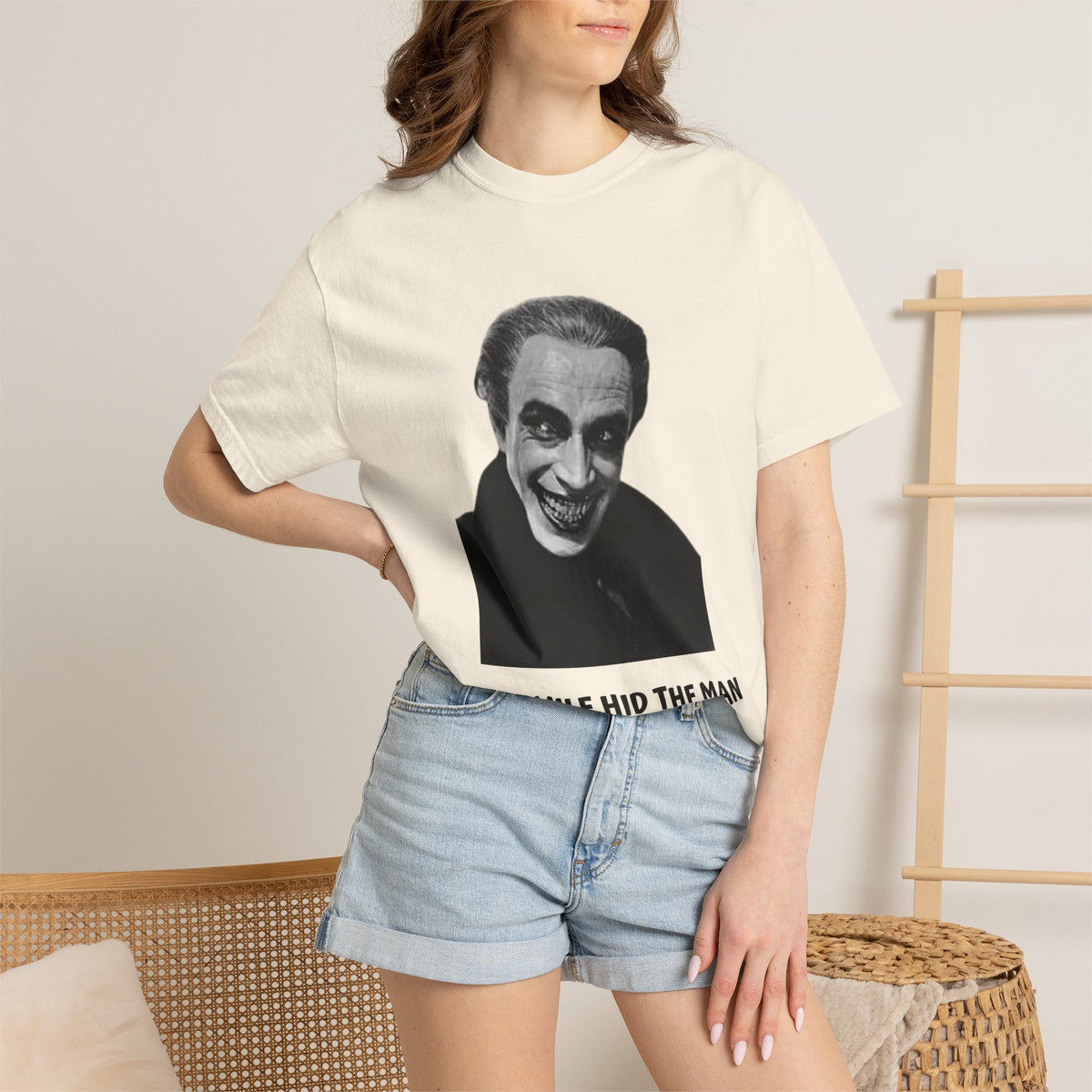 The Man Who Laughs Gwynplaine T-shirt in Chambray blue, worn outside a bookshop — 'The Smile Hid the Man, Gwynplaine 1869'