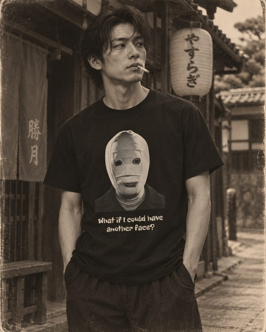 Sepia photograph of a man on an old street at evening, cigarette at his lips, wearing a shirt printed with a bandaged face and the words: what if I could have another face?